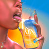 A person holding and licking a can of  ​​Kin Euphorics Actual Sunshine. Can and persons nails are blue and yellow. Person is wearing gold jewelry  Thumb