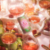 A can of ​​Kin Euphorics Kin Bloomin in champagne and wine glasses surrounded by a pink snake and red lipstick. Thumb